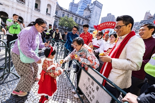 图为巡游队伍沿途给游客送出祝福吉祥的金元宝。澳门特区政府新闻局供图