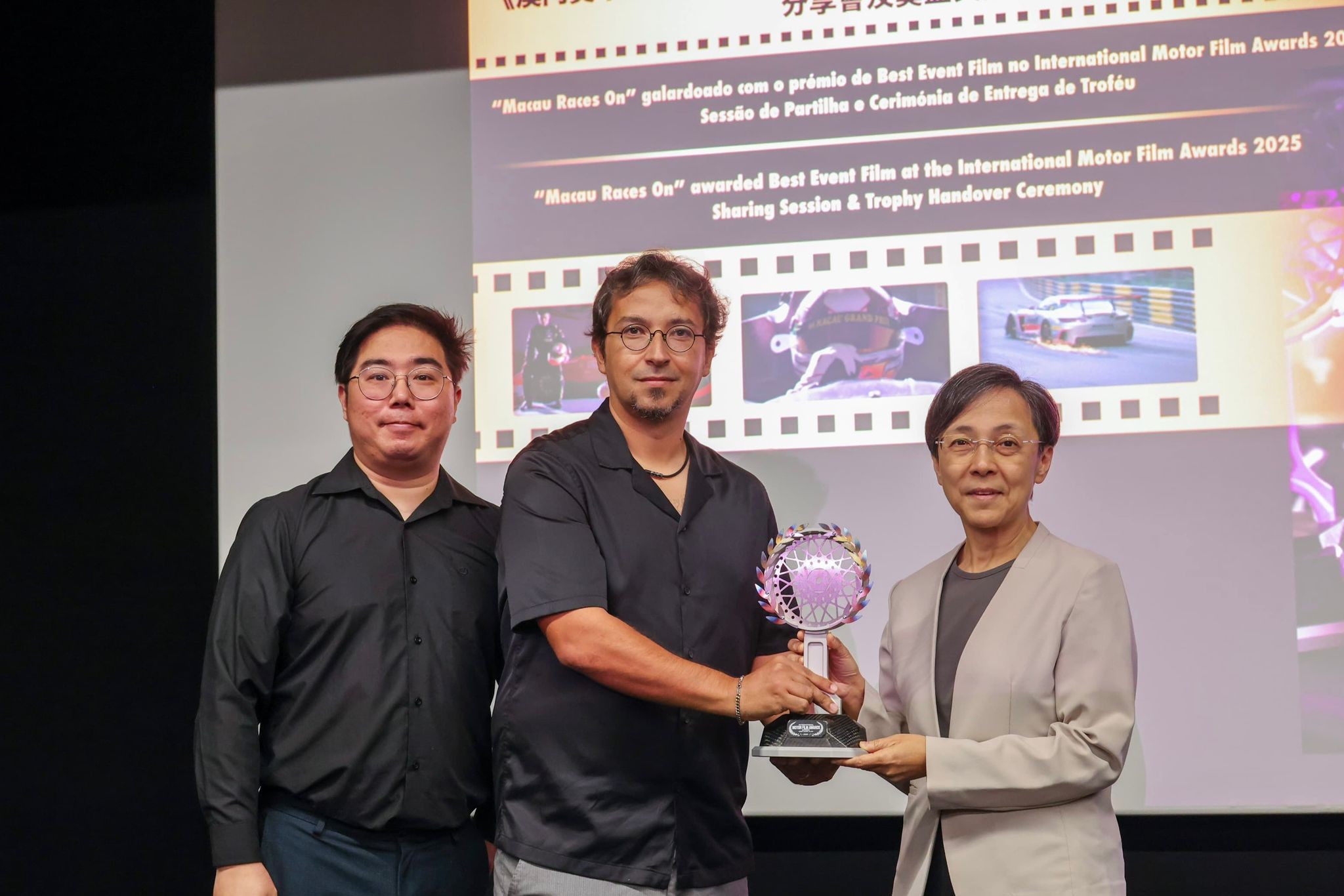 图为文绮华（右）从影片导演手中接过奖杯，作为澳门大赛车博物馆的馆藏。澳门特区政府旅游局供图