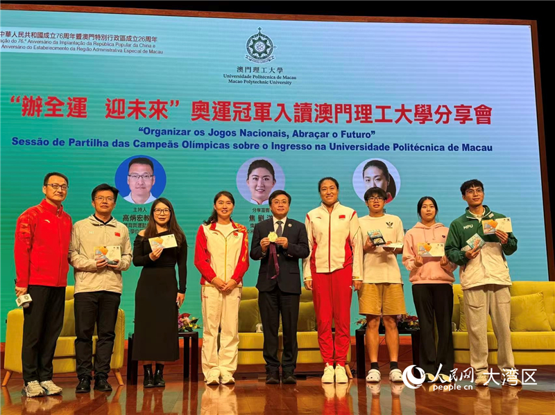 图为两位冠军为现场互动提问的同学们送上纪念品。（本报记者富子梅摄）