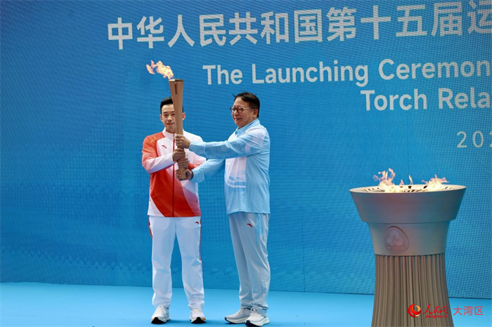 香港站首棒火炬手黄镇廷从香港特区署理行政长官陈国基手中接过圣火。人民网 严小晶摄