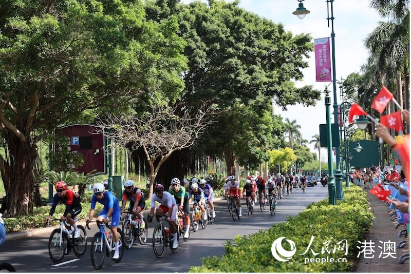 比赛车队经过观赛区，观众挥舞旗帜呐喊助威。人民网记者 冯学知摄