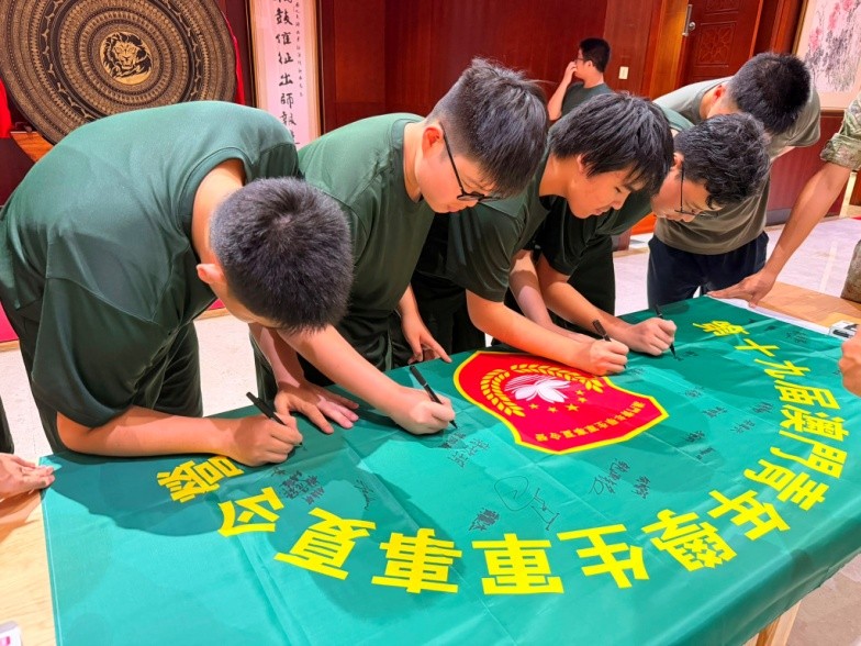 图为学员们在营旗上签名留念。主办方供图
