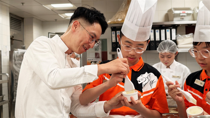 图为吴梓佑同学（左二）在父亲吴永谋（左一）指导下制作甜品。主办方供图