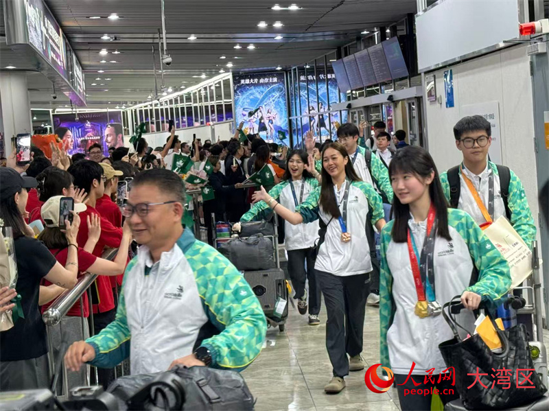 图为澳门代表团载誉而归，在澳门国际机场受到热烈欢迎。图中右一、右二、右三分别为银牌、金牌、铜牌获得者。人民网记者 富子梅摄