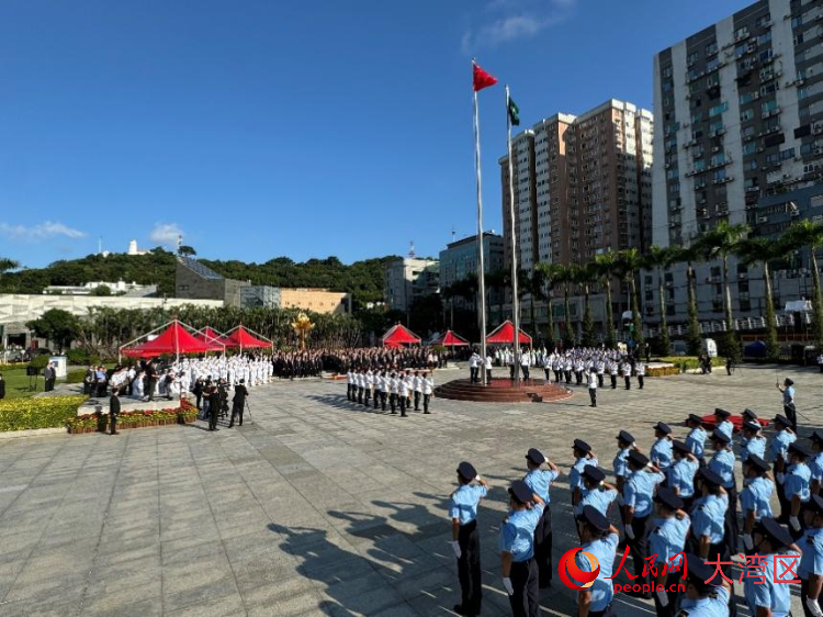 图为中华人民共和国国旗与澳门特区区旗冉冉升起，随风飘扬。人民网记者 富子梅摄