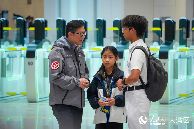 图6:香港特区政府保安局局长邓炳强向旅客询问过关情况。人民网 吴宇扬扬摄