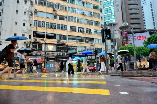 8月2日，人们撑伞走在雨中。当日，香港天文台再一次发出黑色暴雨警告信号。这是一周内连续发出的第二个黑色暴雨警告。新华社记者 朱炜 摄