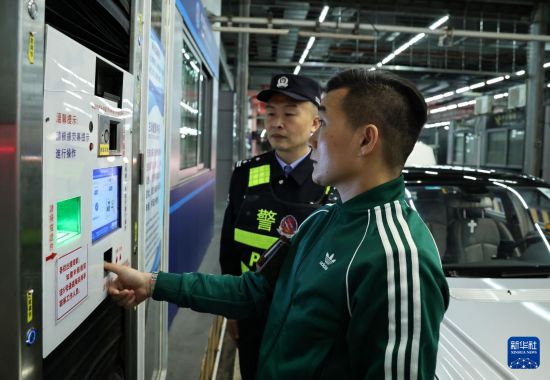 12月23日零时,“粤车南下”入境香港市区的通关车主曹先生(前)在“一站式”通道办理通关手续。新华社记者 黄国保 摄