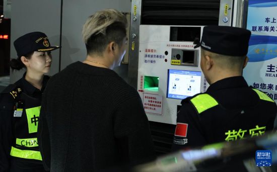 12月23日，“粤车南下”入境香港市区的首位通关车主彭先生（中）在“一站式”通道办理通关手续。新华社记者 黄国保 摄