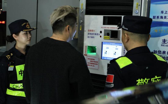 12月23日，“粤车南下”入境香港市区的首位通关车主彭先生（中）在“一站式”通道办理通关手续。新华社记者 黄国保 摄