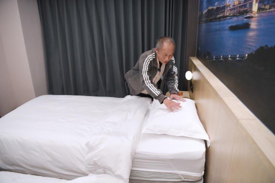 2025年11月28日，宏福苑居民邝佩麟在粤海酒店“爱心客房”里整理床铺。新华社记者 陈铎 摄