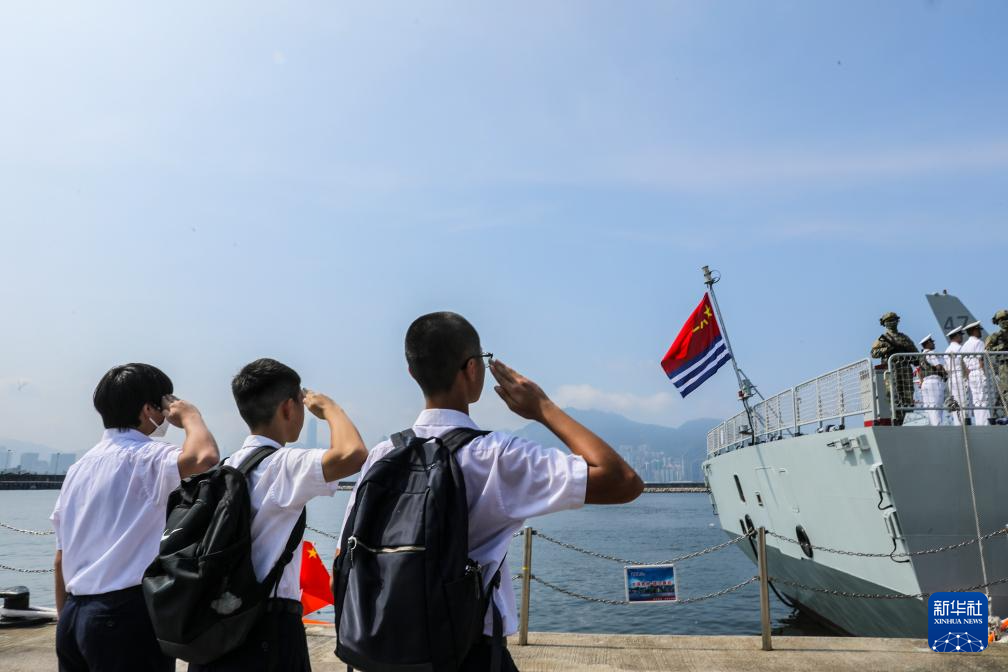 7月7日，湛江舰即将驶离昂船洲军营码头，三名香港福建中学的学生向悬挂在舰尾的海军军旗敬礼。新华社发（冯丽 摄）